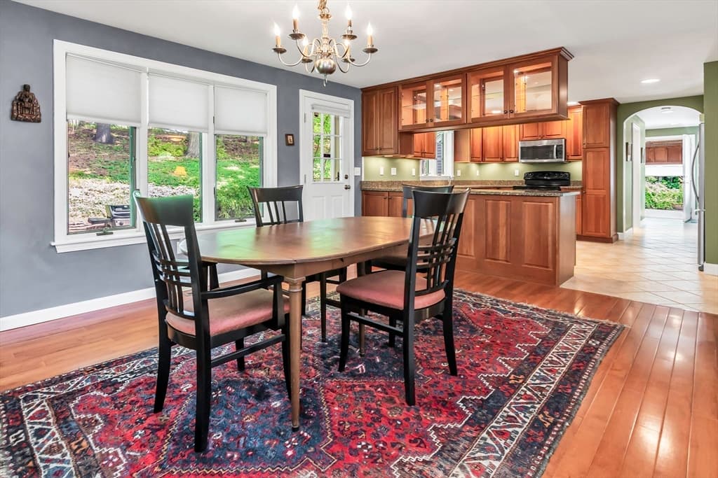 Dining area opening to a bright kitchen with wood floors